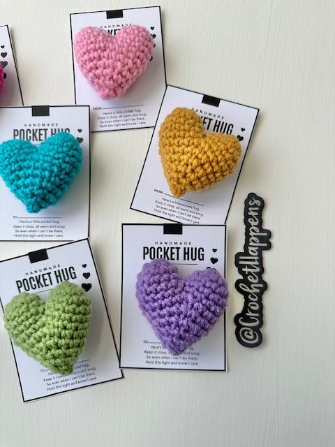 close up of collection of hand crocheted pocket hugs stuffed hearts on gift cards right side